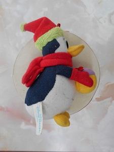 赤い帽子、マフラー、手袋をしたペンギンのぬいぐるみの横からの写真