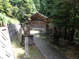 手前には石碑、奥には油瀧神社（上之宮）が見える写真