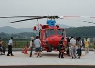 大きな赤いヘリコプターと見学する人々の写真