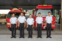 消防車の前で整列する、新人消防士たちの写真