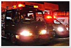 夜の緊急出動にあたり、ライトと赤色灯を点灯している消防車と救急車の写真