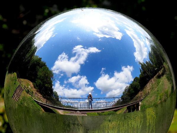 鏡面の球に自分と晴天の空を写している