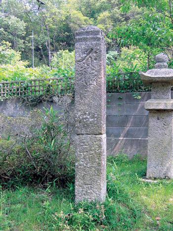 石造方柱碑と背景には石塀と石灯籠の写真