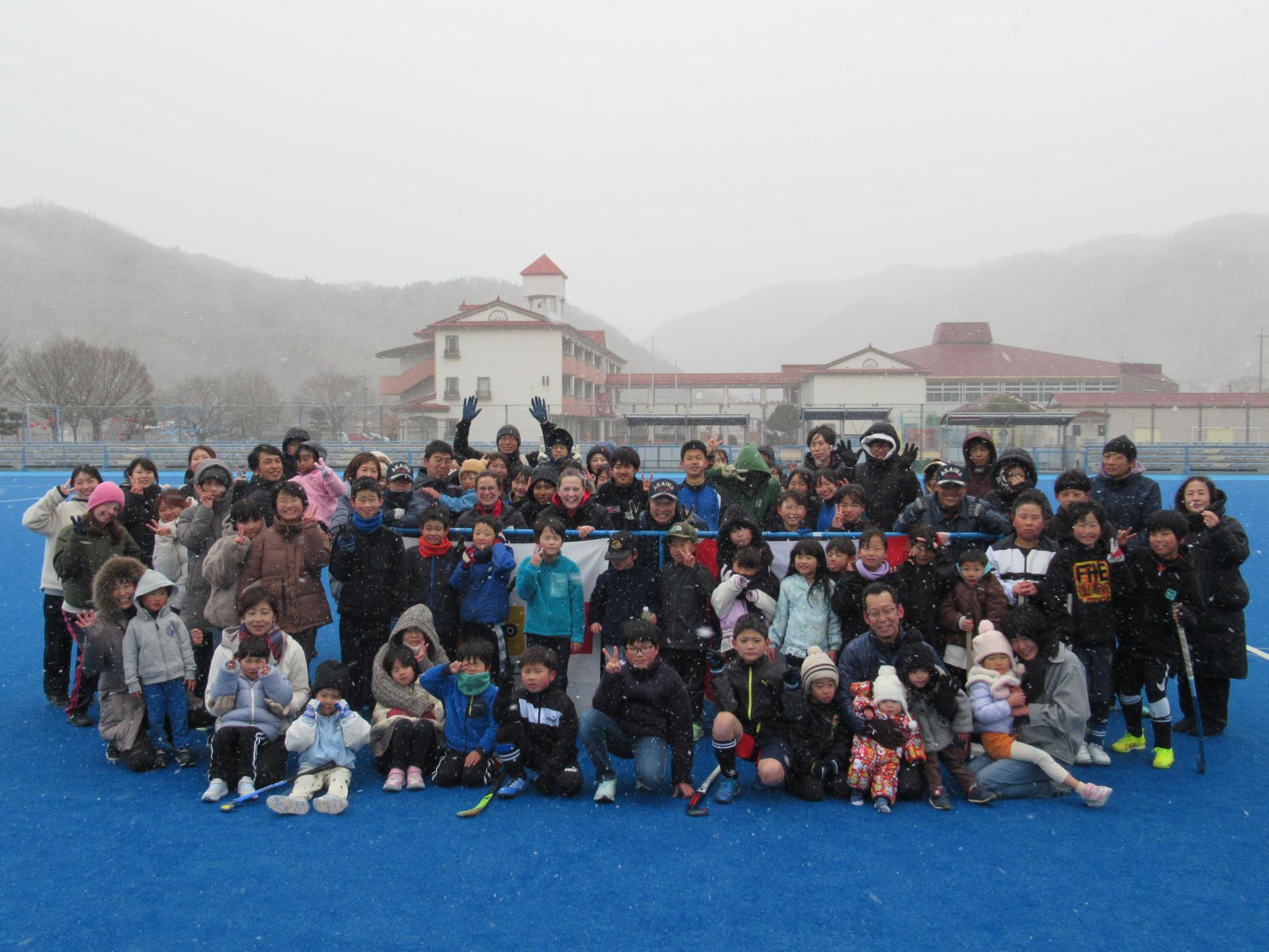雪降る中集合写真に納まる参加者