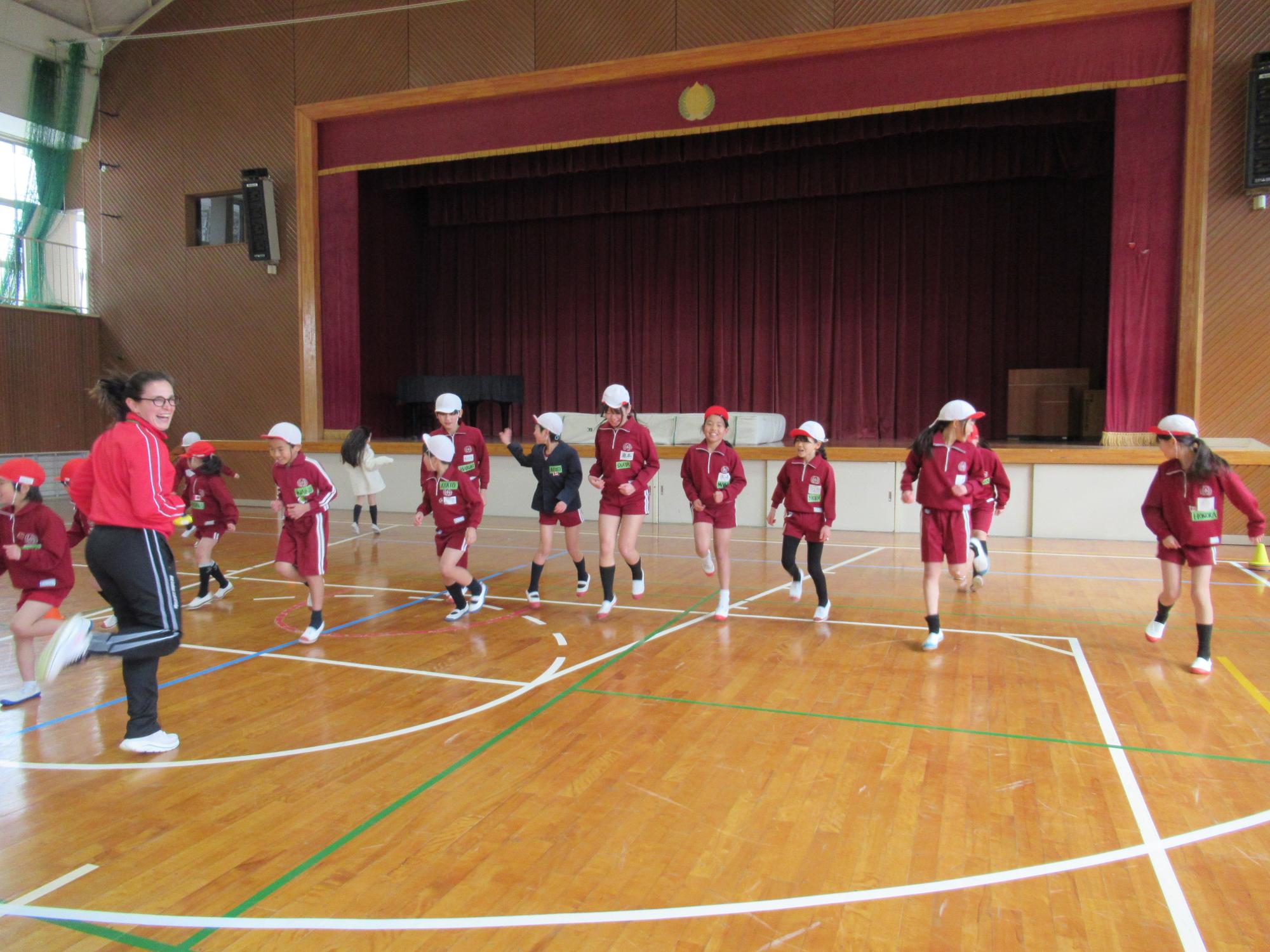 スキップをしてウォーミングアップをするコーチと小学生