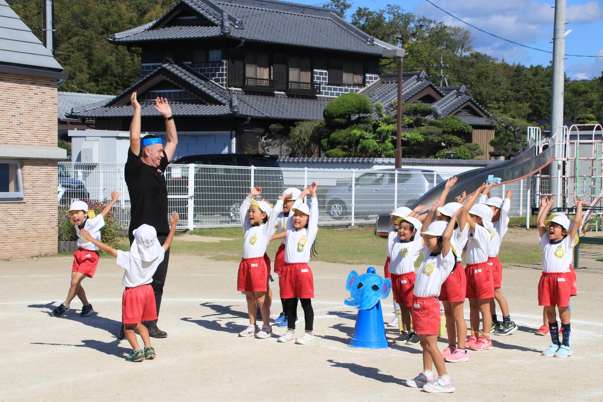 バンザイでお祝いをする園児とオレインさん