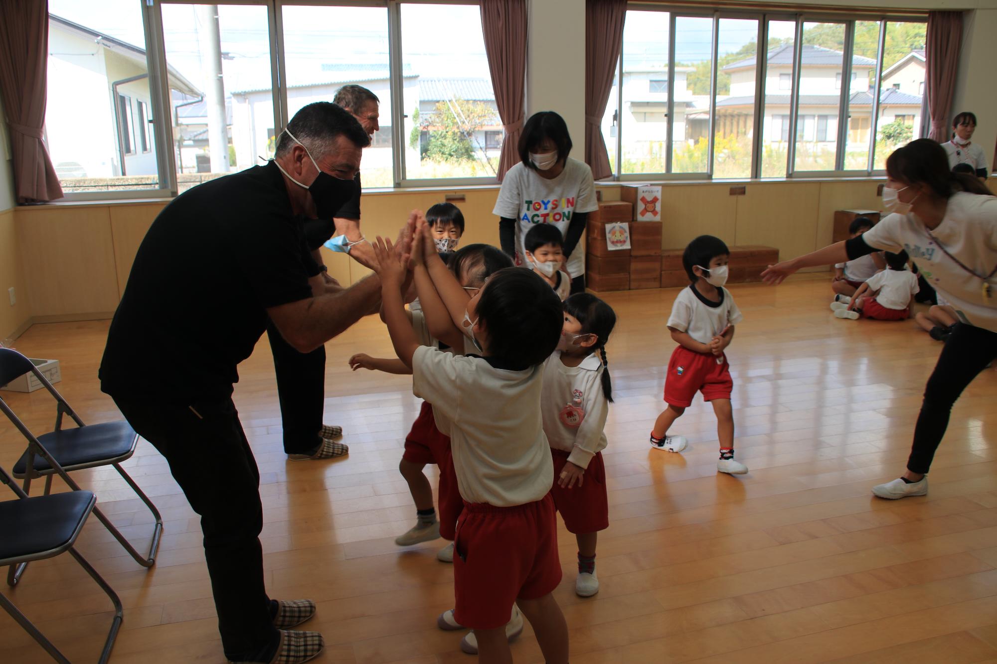 ハイタッチでお別れをする園児とオレインさん