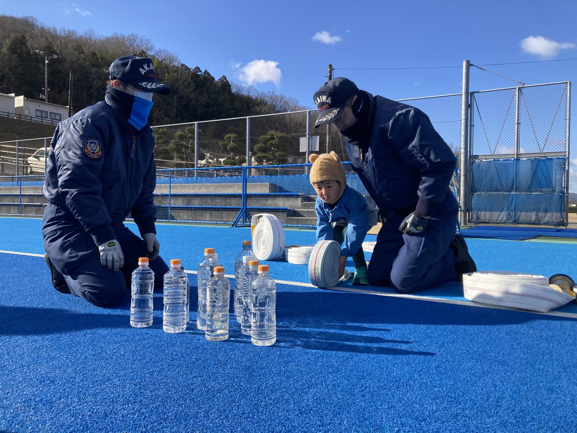 消防ホースでボーリングのようにボトルを倒すチャレンジをするこども