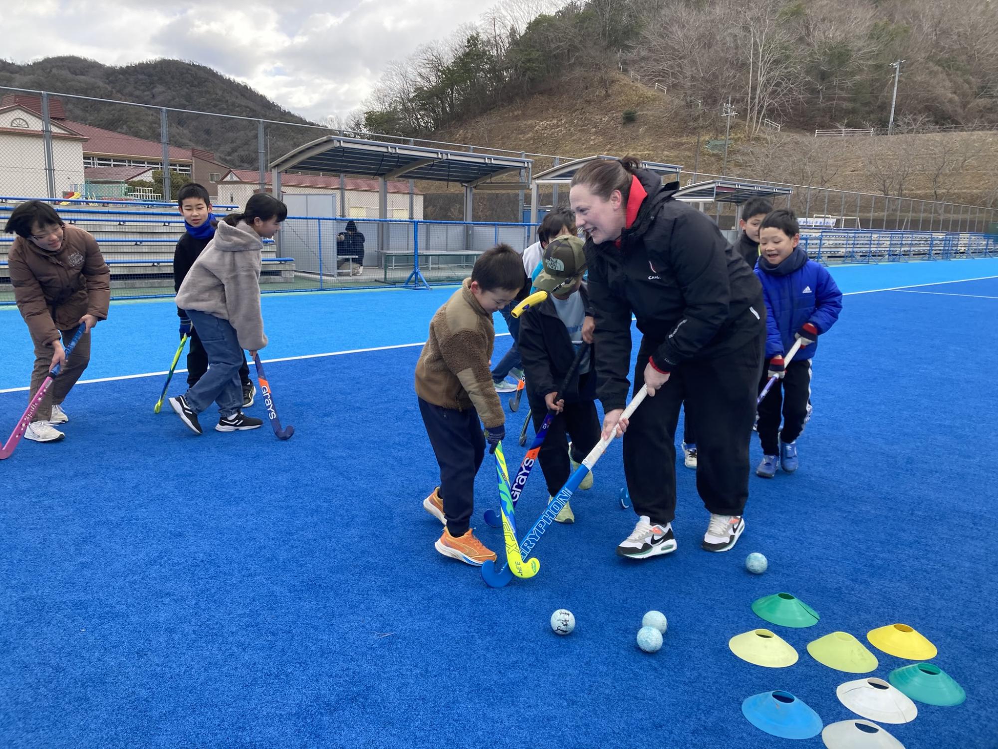 カナダコーチに続いてスティックでドリブルにチャレンジする参加者