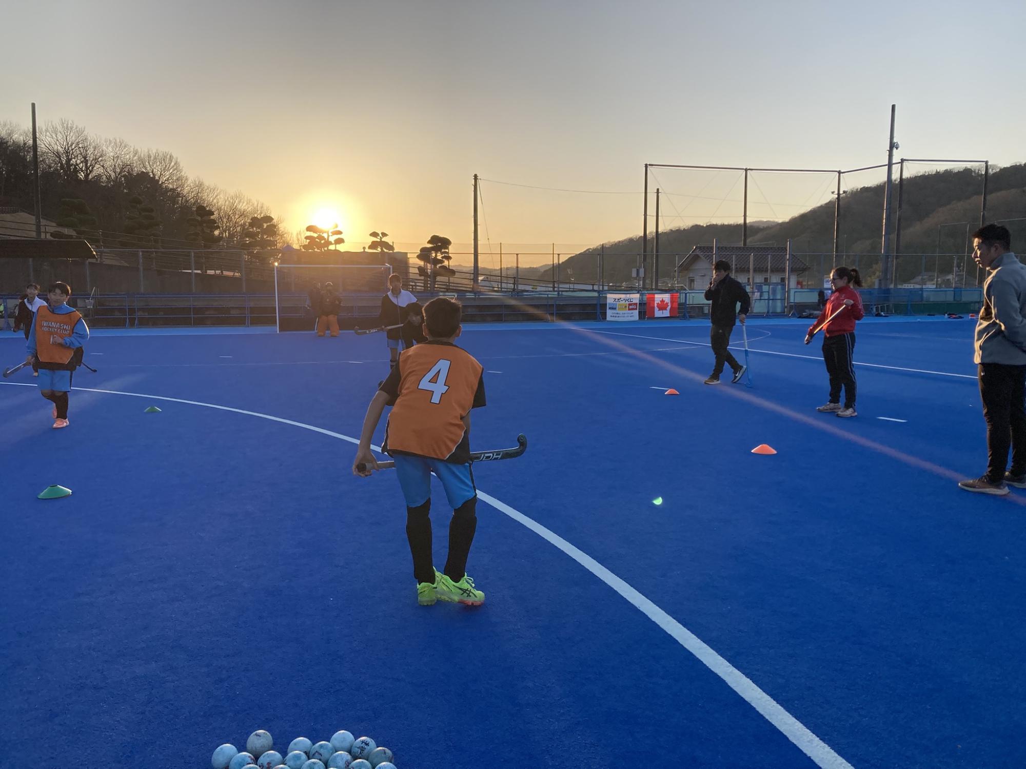 夕暮れに交流するコーチと中学生