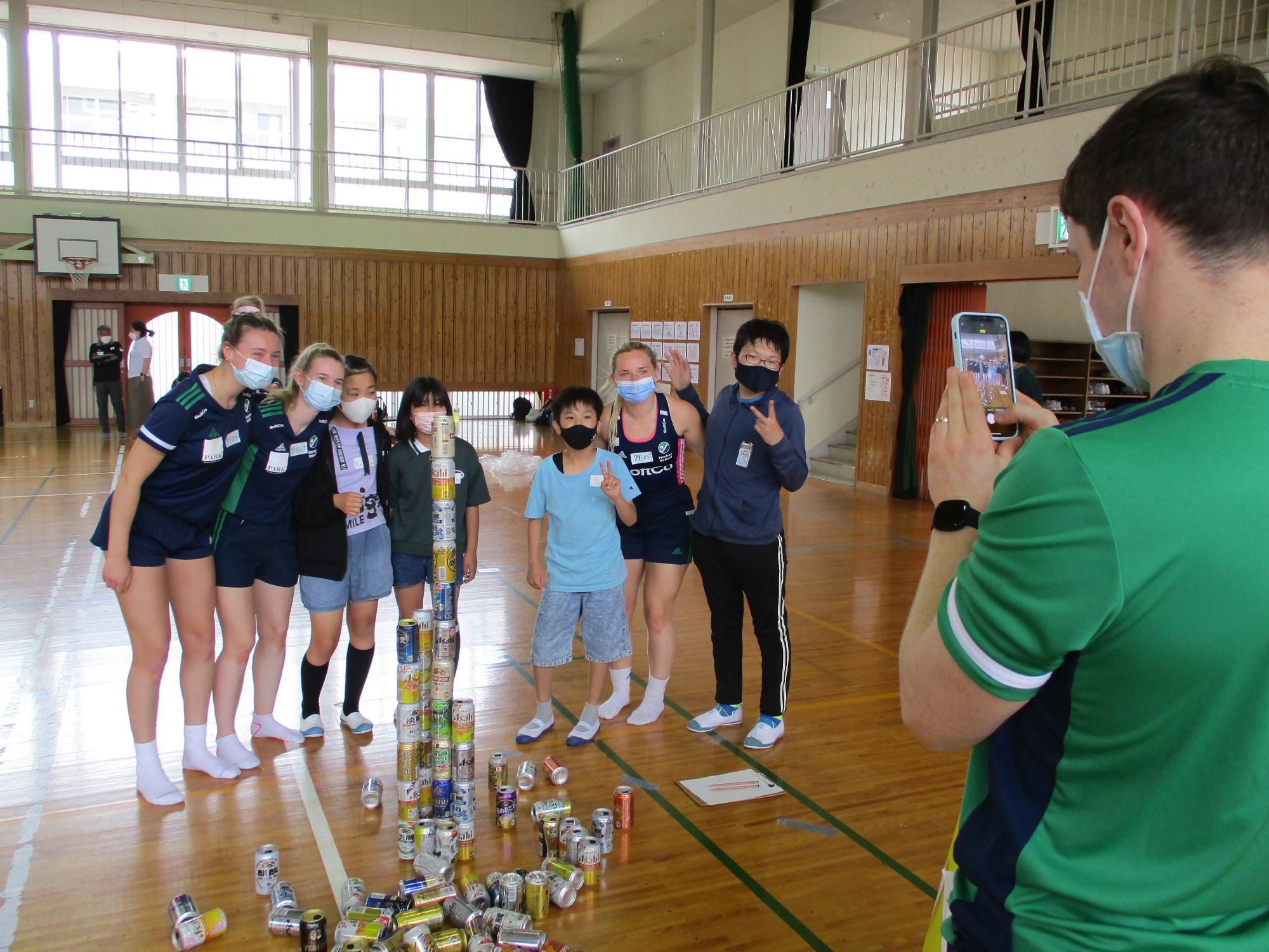 作った空き缶タワーの前で記念写真をとる6年生と選手たち