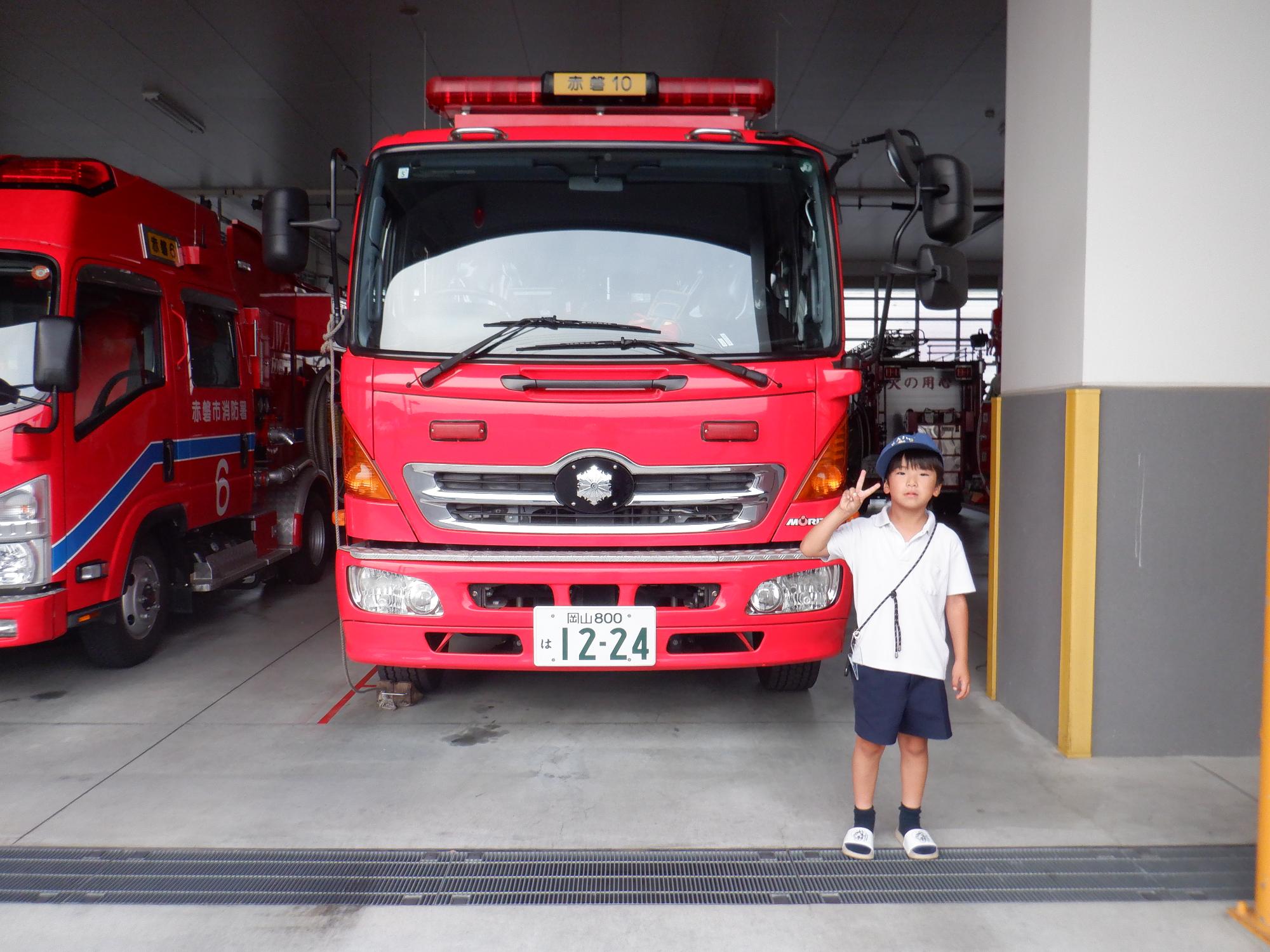 消防車の前で少年がピース