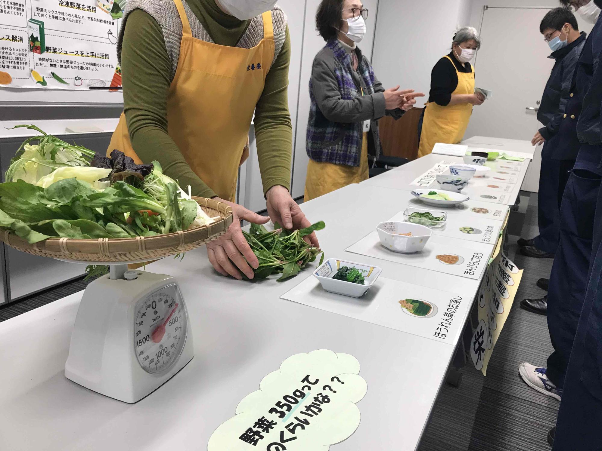 解説する栄養委員の方々と野菜のサンプル