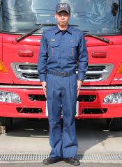 消防車の前で活動服を着て立つ職員の写真