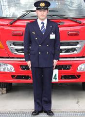消防車の前で制服（冬服）を着て立つ職員の写真
