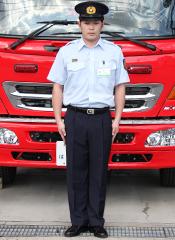 消防車の前で制服（夏服）を着て立つ職員の写真